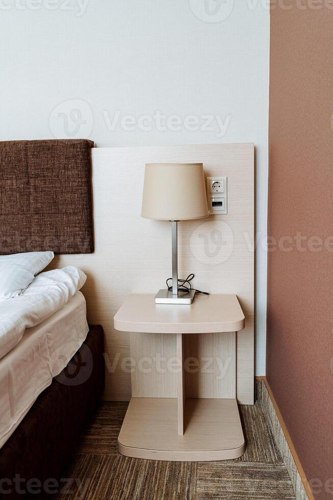 The beautifully designed bedroom includes a plush bed and an elegant nightstand with a stylish lamp, creating a serene atmosphere perfect for relaxation and restful sleep photo