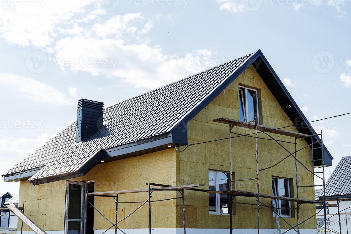 Currently, a house is actively being constructed, and there is scaffolding surrounding the structure to support the building process and provide safety for workers and materials photo
