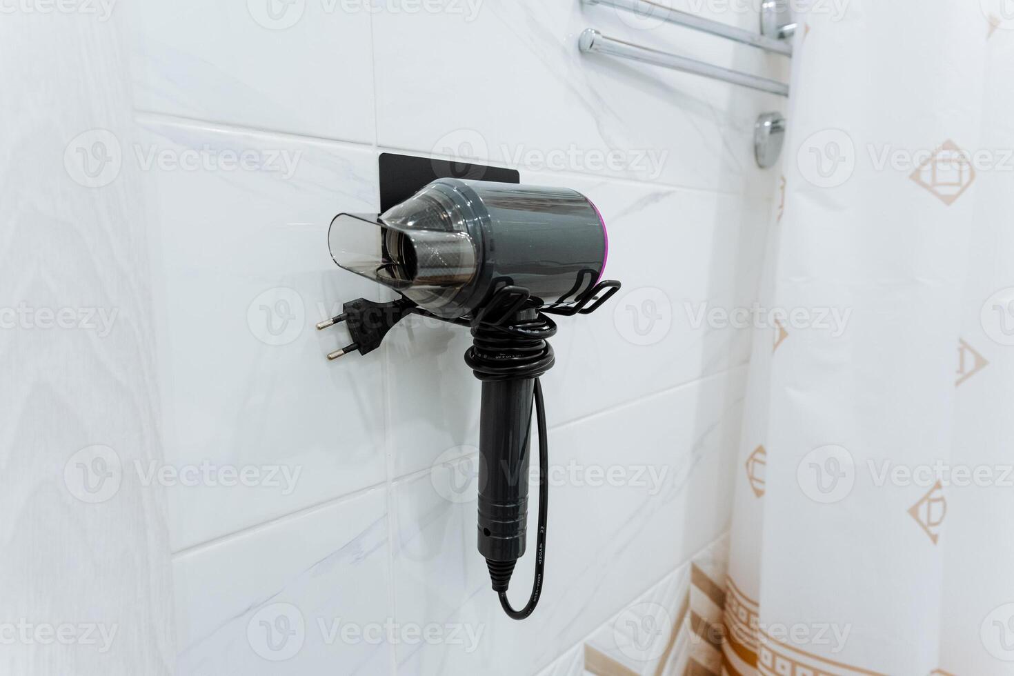 A hair dryer has been securely mounted on a wall within a compact bathroom space, offering great convenience for users who need to style or dry their hair effectively after a shower or wash photo