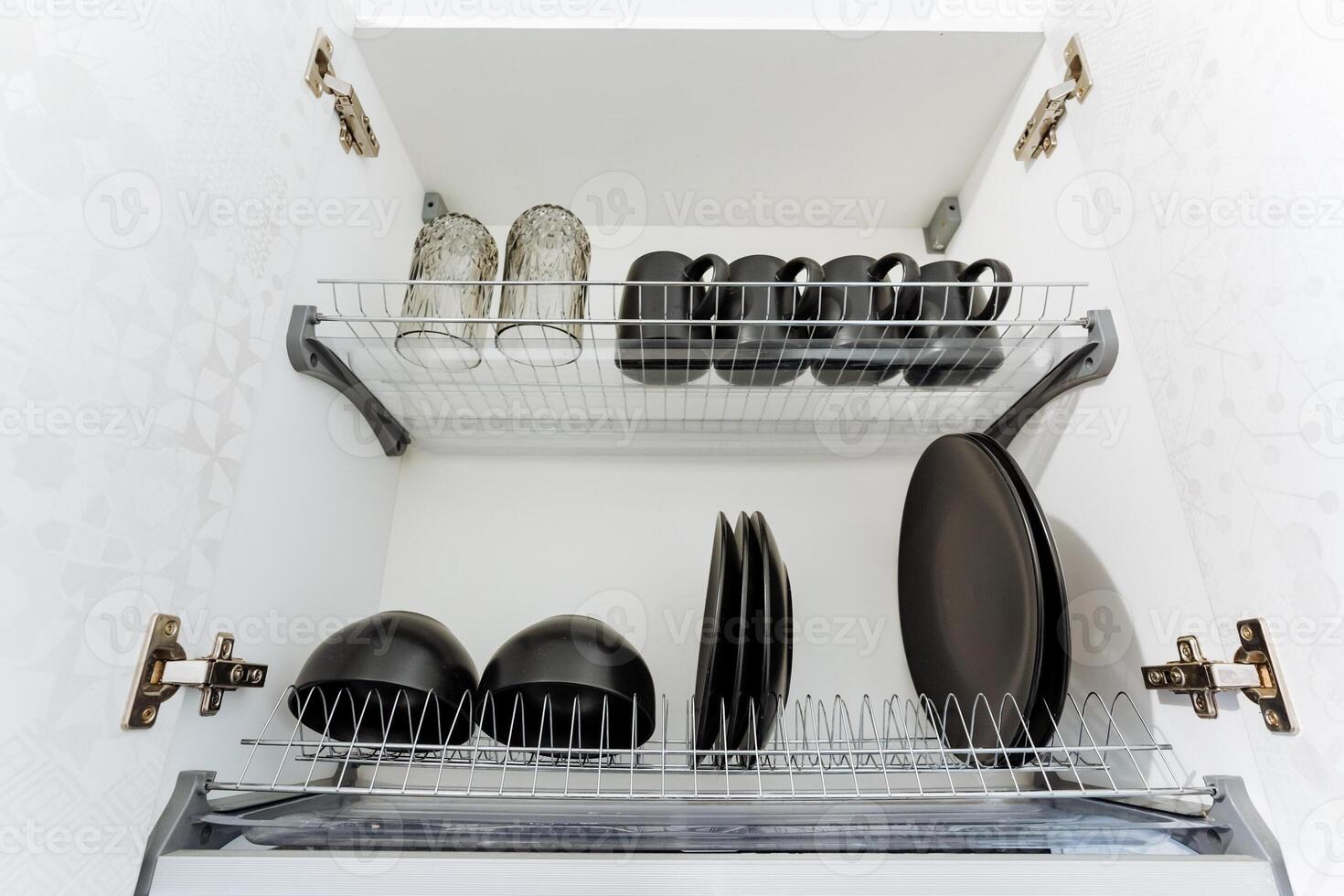 A dish rack that is filled with various items such as plates, cups, and pans, making it a useful kitchen accessory for organizing and drying dishes efficiently after washing them photo
