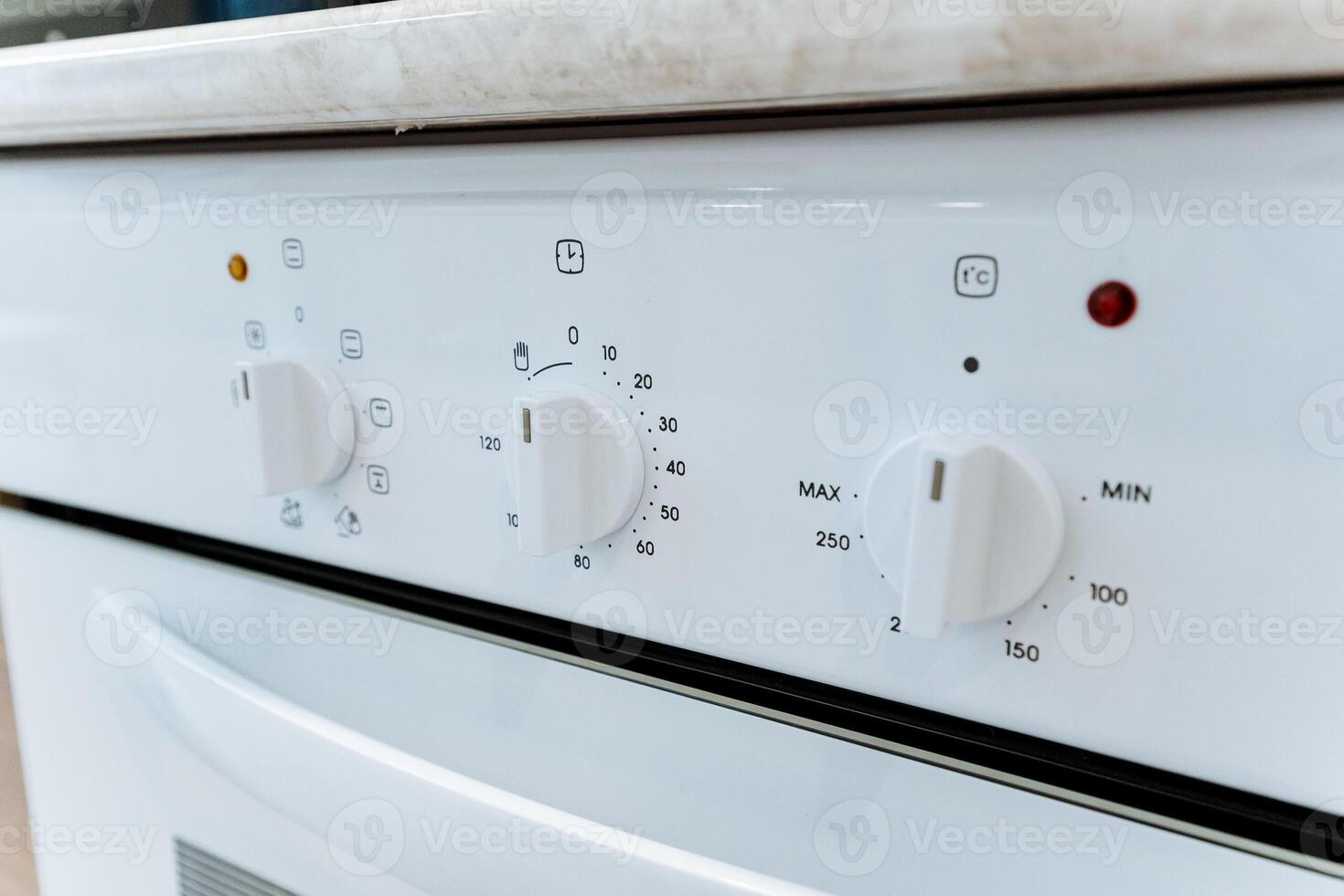 This image shows a closeup of a pristine white oven, highlighting its immaculate design with white knobs and a red light indicator, showcasing modern kitchen aesthetics photo