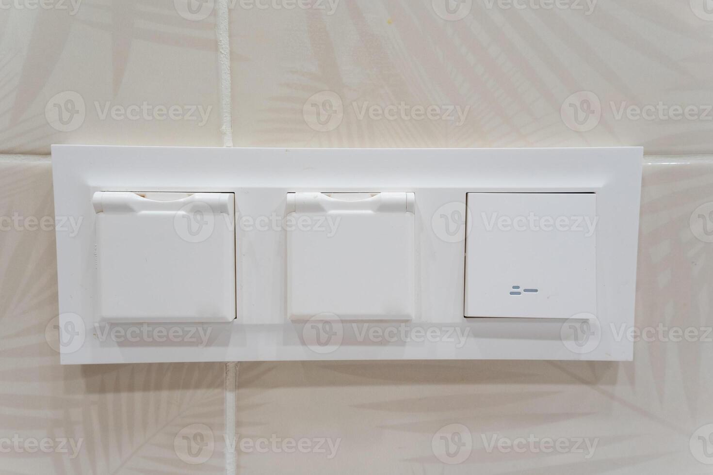 Close up image of a white light switch on a tiled wall photo