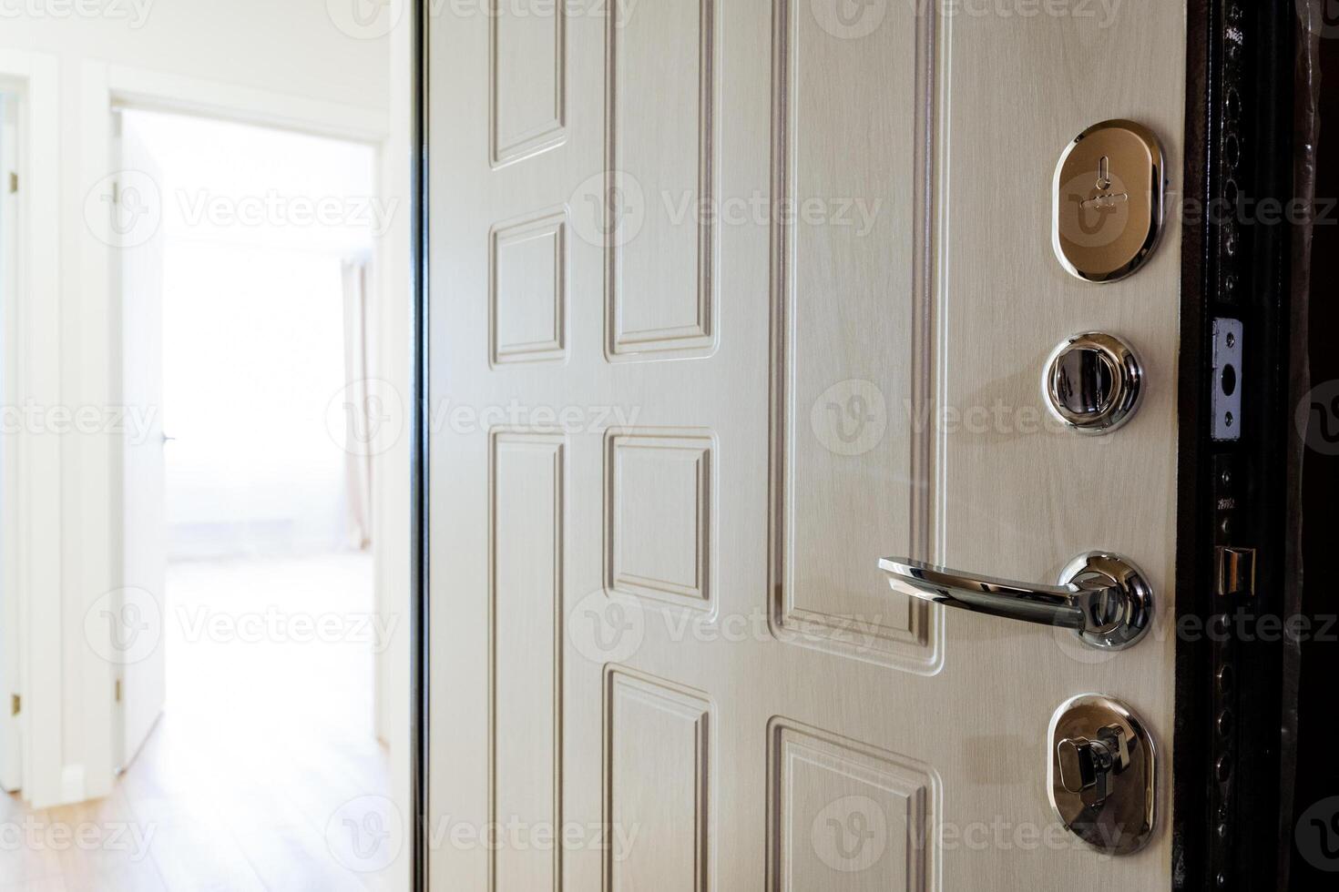 White door with chrome handle open to hallway in building photo