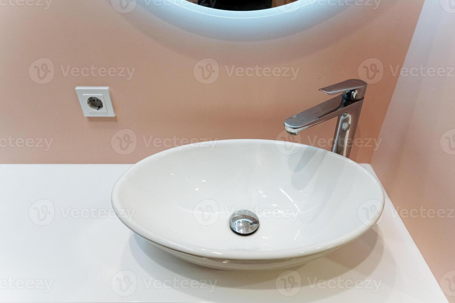 The bathroom sink is beautifully designed with a sleek faucet and accompanied by a stylish mirror positioned above it, which together create a serene and elegant atmosphere in the space photo