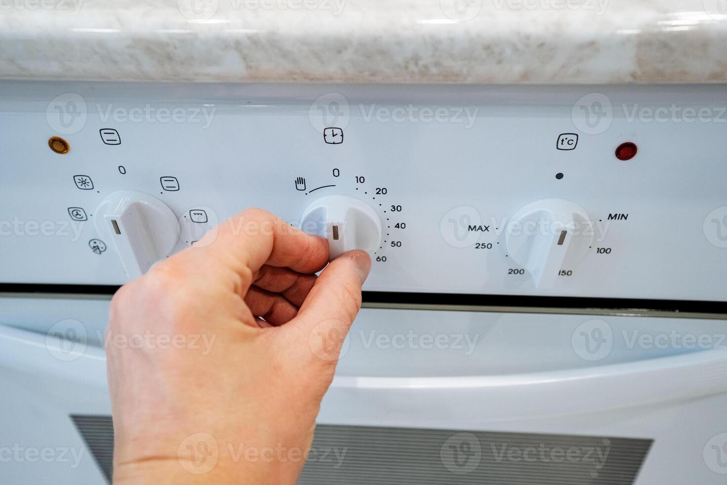 A person is carefully turning a knob located on a white oven that is presumably used for cooking or baking various delicious meals and treats in the kitchen, a vital home appliance photo