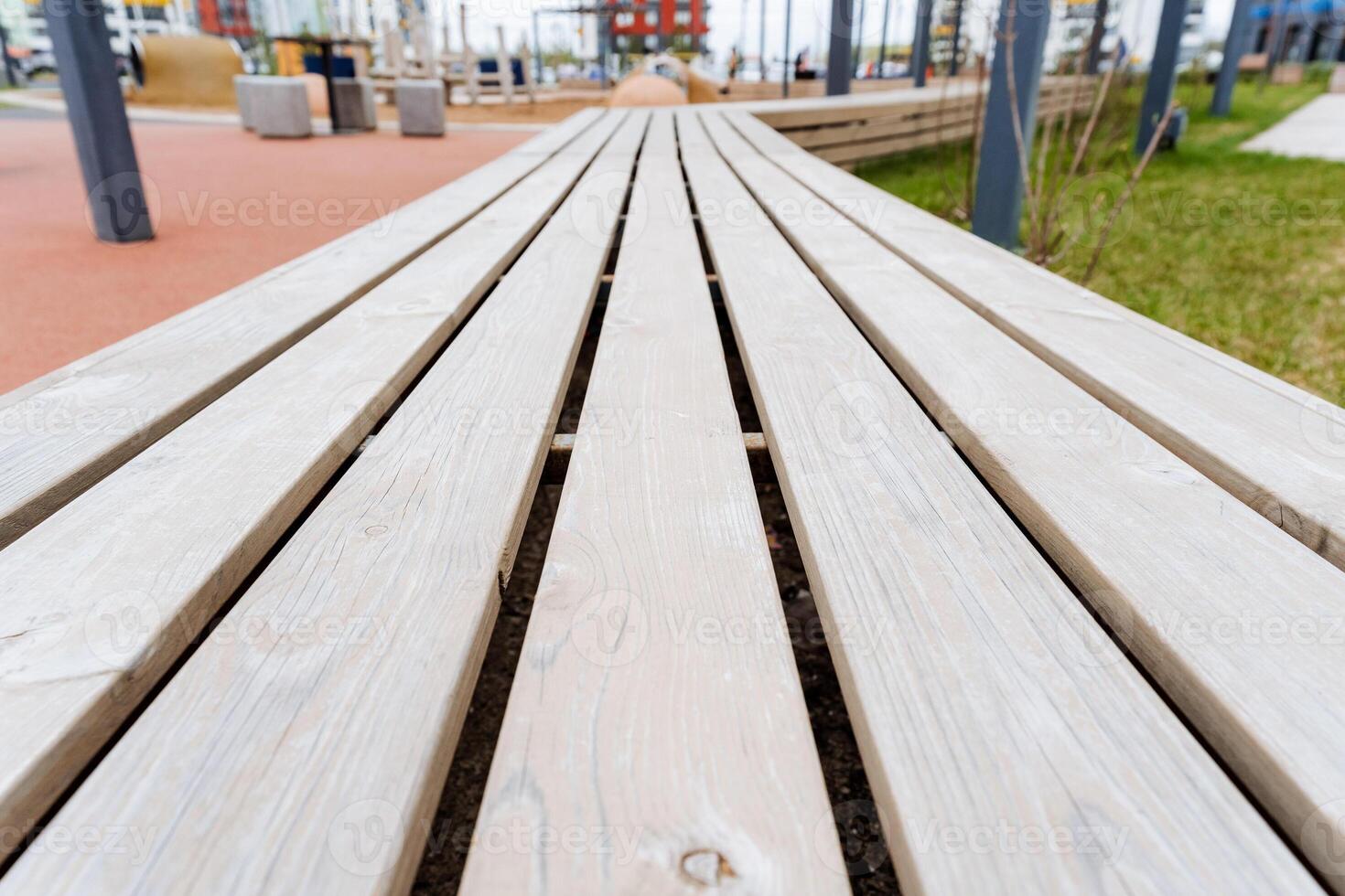Closeup of hardwood bench with parallel wooden planks in park photo