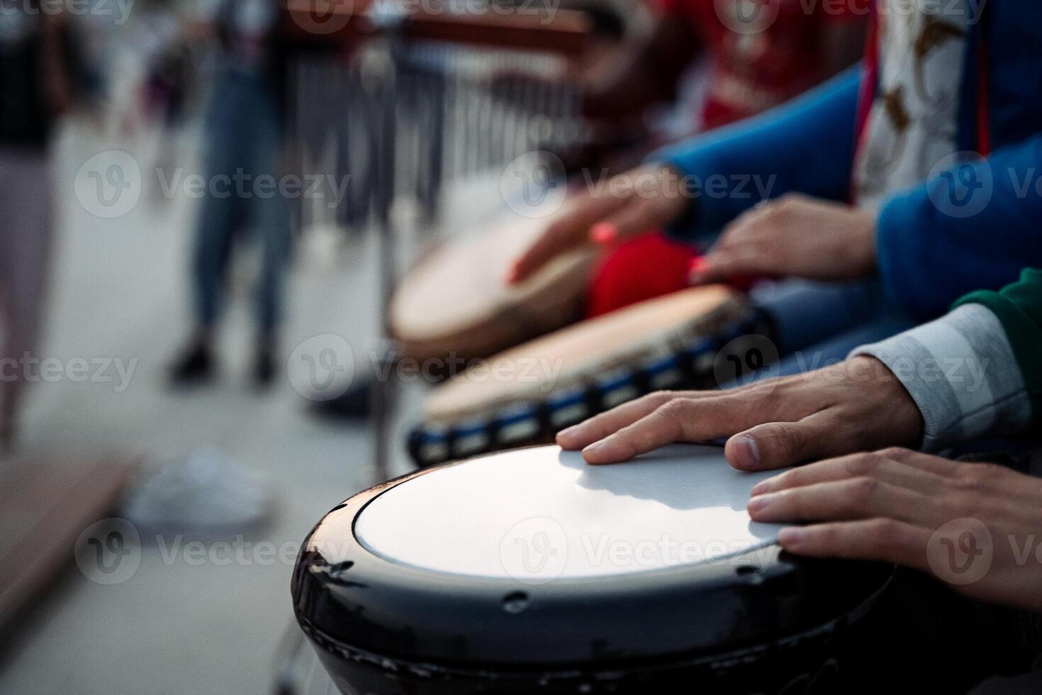 A group of hands skillfully playing drums in a vibrant outdoor setting, creating a lively atmosphere filled with music and rhythm photo