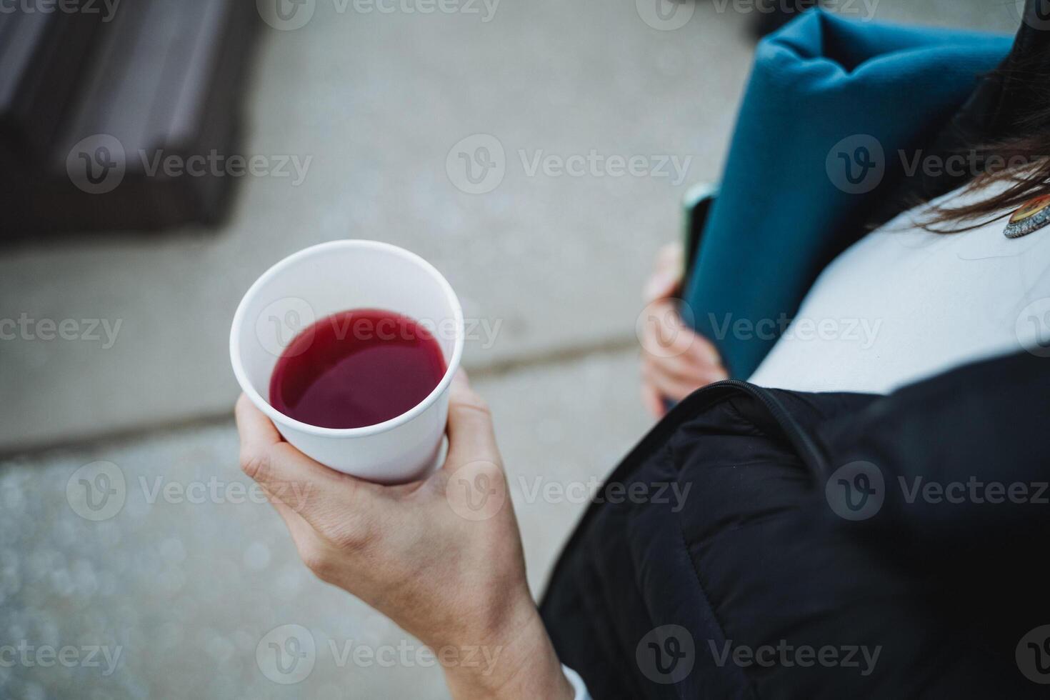 A woman is holding a cup filled with a red beverage while surrounded by various documents and paperwork photo