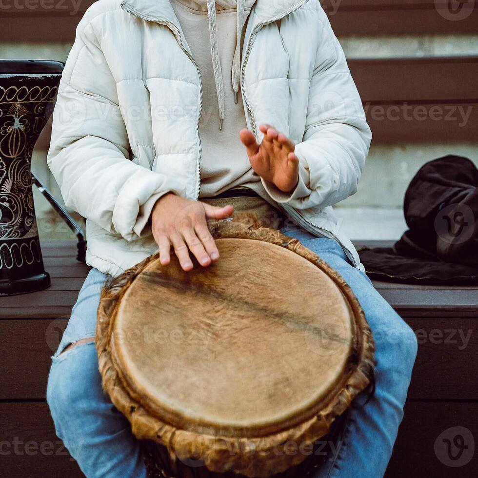 A person is playing a traditional drum in an outdoor setting, creating a vibrant atmosphere filled with cultural music and rhythmic sounds photo