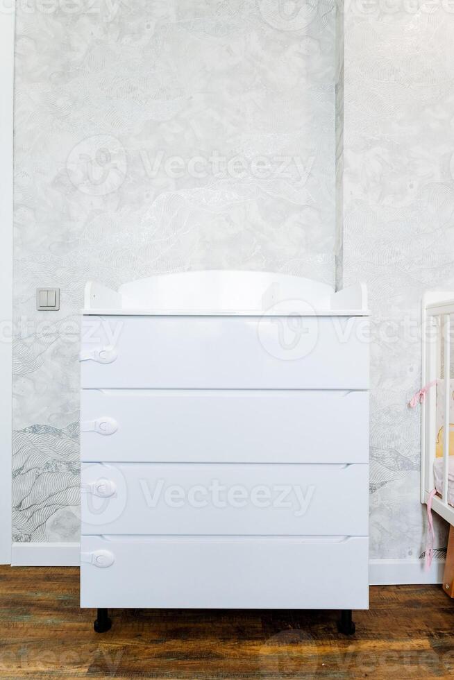 Wood chest of drawers on wheels by crib in nursery photo