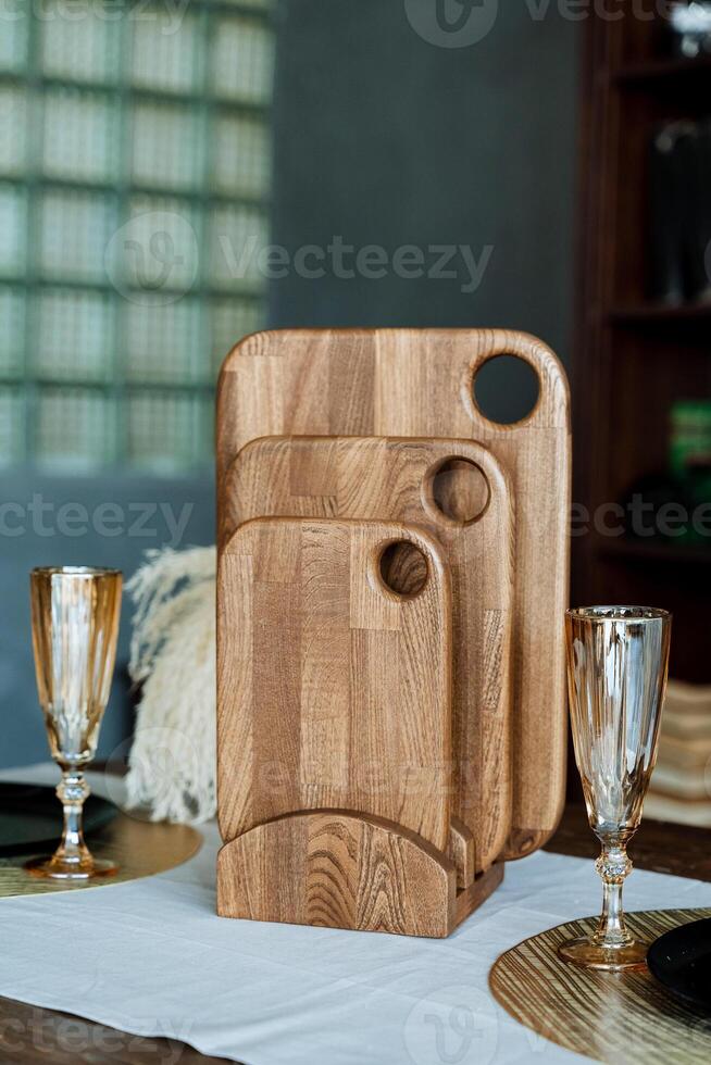 Three beautifully crafted wooden cutting boards are thoughtfully stacked on top of one another upon a sturdy table, showcasing their unique designs and rich wood grain patterns photo