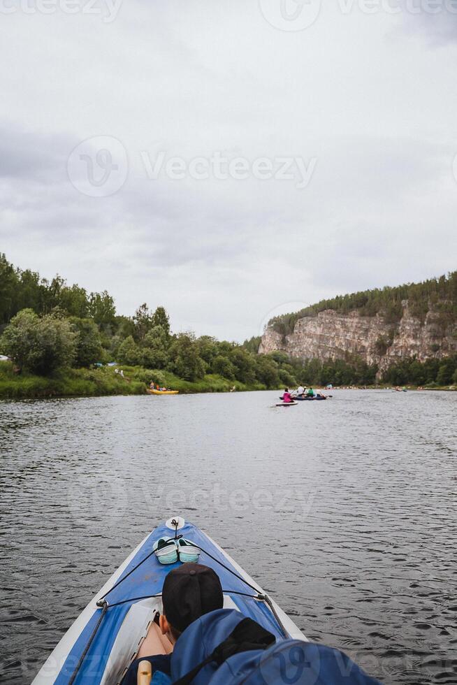 A man is comfortably and contentedly sitting in the back of a boat that is gently floating on a serene river, surrounded by lush nature and the breathtaking beautiful scenery around him photo