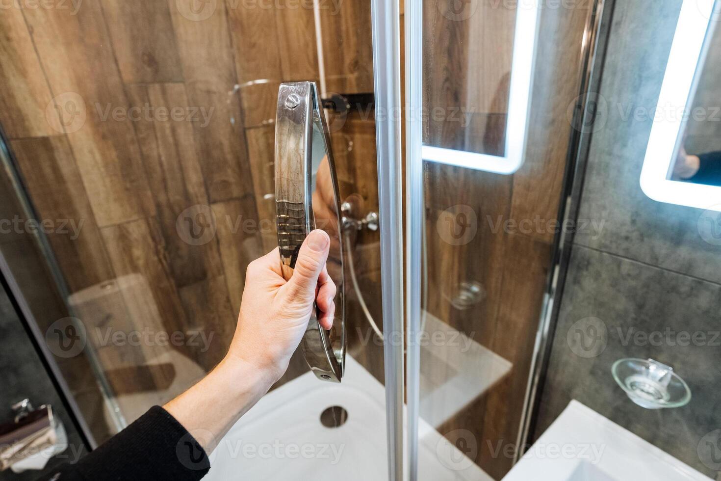 A person is in the process of opening a shower door in a bathroom, which is typically found in residential homes for personal hygiene and bathing purposes, enjoying a refreshing experience photo