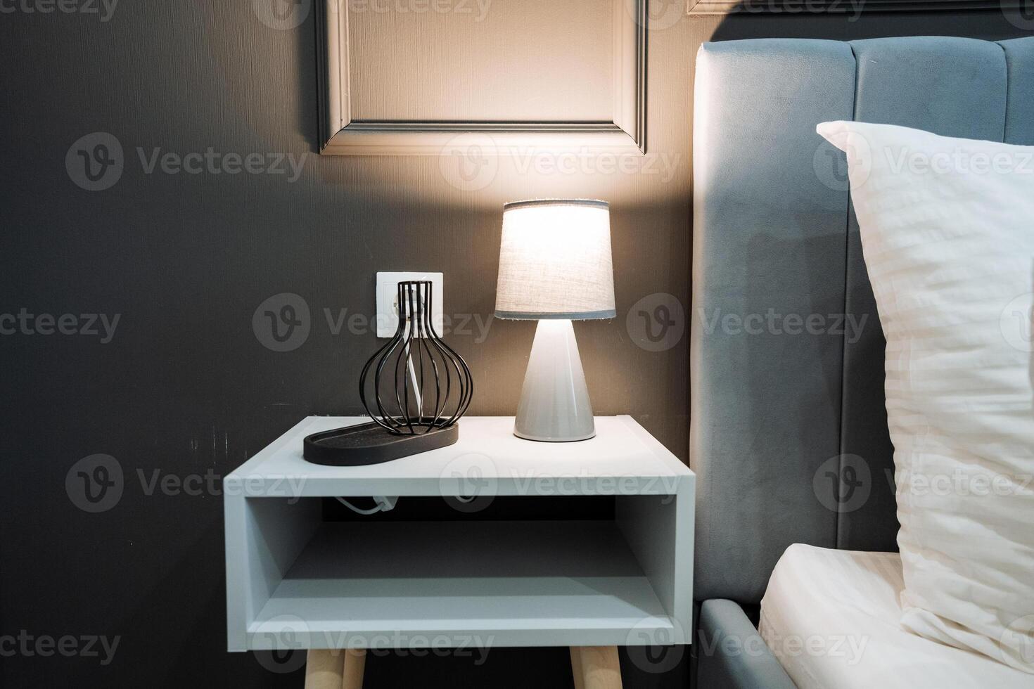 A stylish nightstand featuring a beautifully designed lamp sits next to a warm, inviting bed in a cozy bedroom, together creating an atmosphere that is perfect for complete relaxation photo