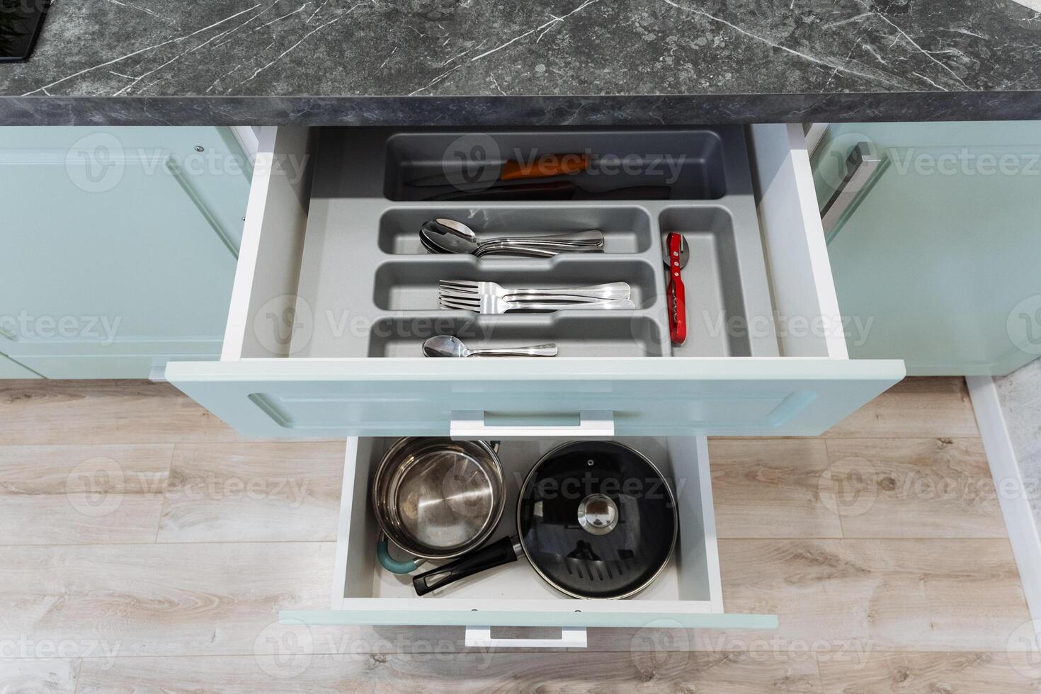 Inside a kitchen drawer, there is a diverse collection that includes various pots, pans, and cooking utensils all organized together for convenient access when preparing meals photo