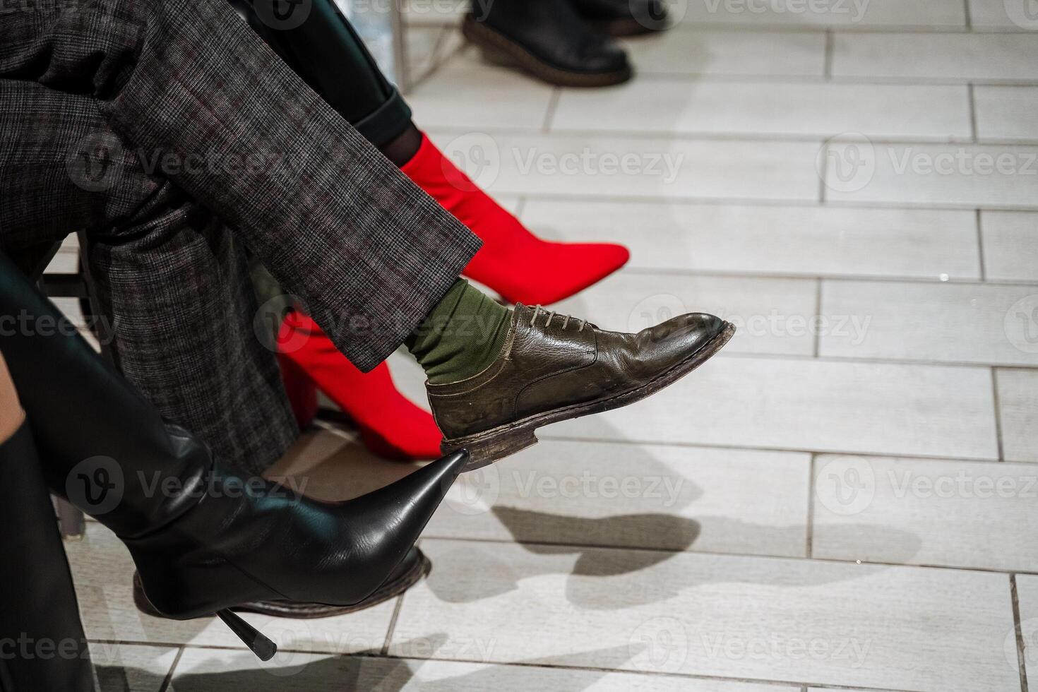 A diverse gathering on a grey floor, with people wearing unique shoes, showcasing a variety of patterns and materials. photo