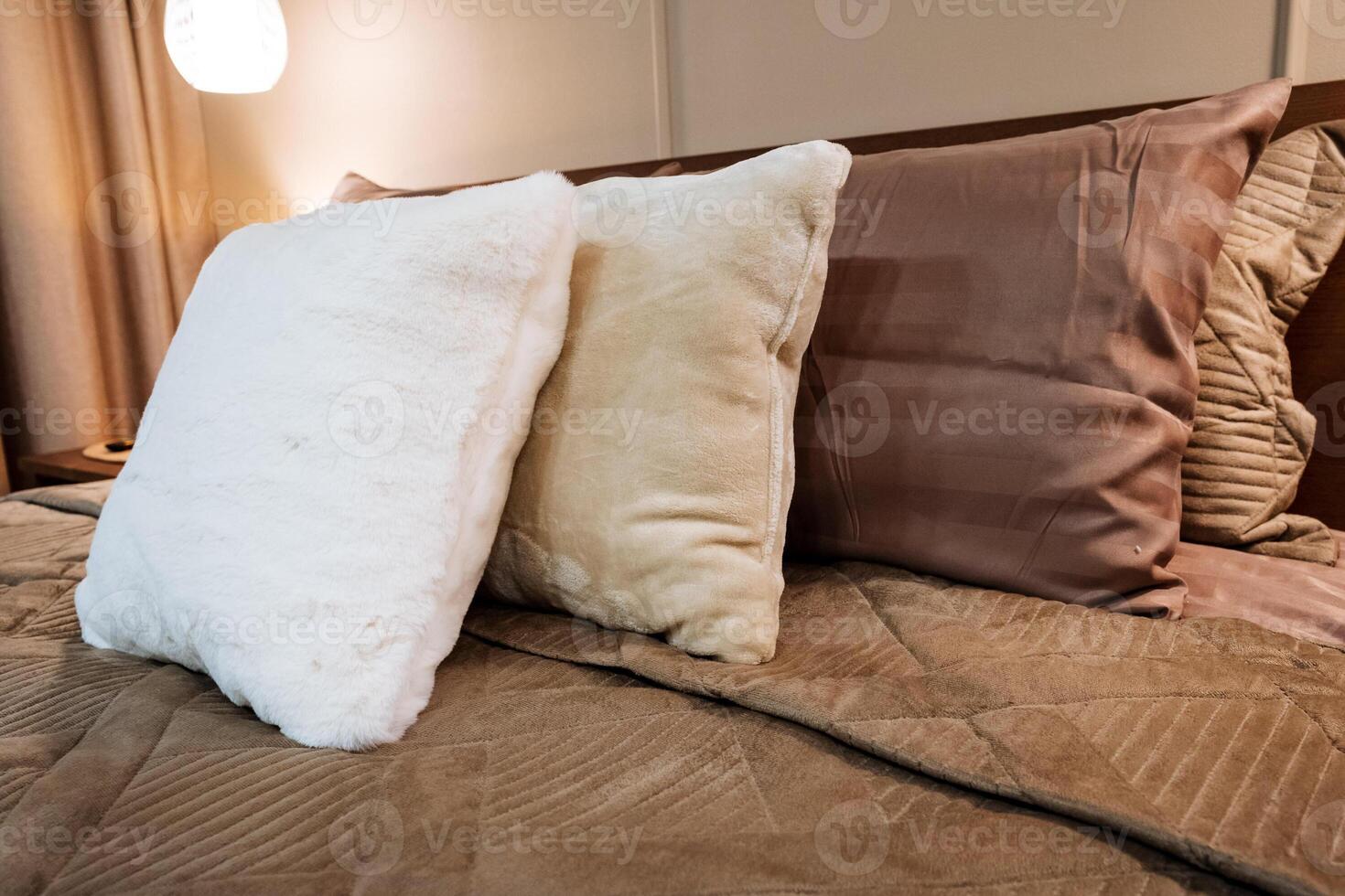 In the cozy room, there are three incredibly soft and fluffy pillows that rest on top of a beautifully and neatly made bed, contributing to a warm, comfortable, and inviting atmosphere photo