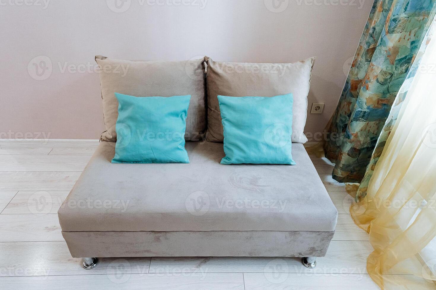 In a cozy living room, there is a stylish chair adorned with two decorative pillows resting on it, positioned next to a window that allows natural light to flood the space photo