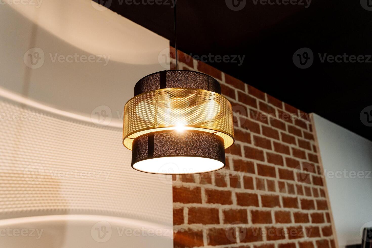 A modern pendant light is placed in a way that its creative shadow patterns enhance the textured brick wall, bringing elegance and chic design to the interior decor photo