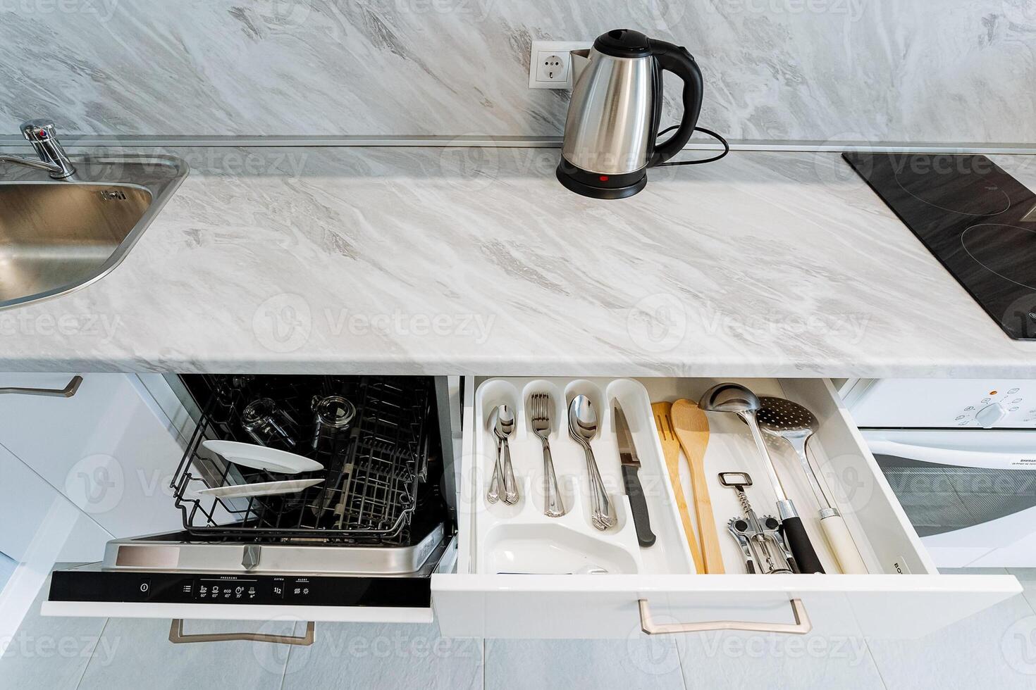 The kitchen is equipped with a sleek, modern dishwasher along with a spacious drawer filled with an array of utensils, making it perfect for all your meal preparation and cooking needs photo