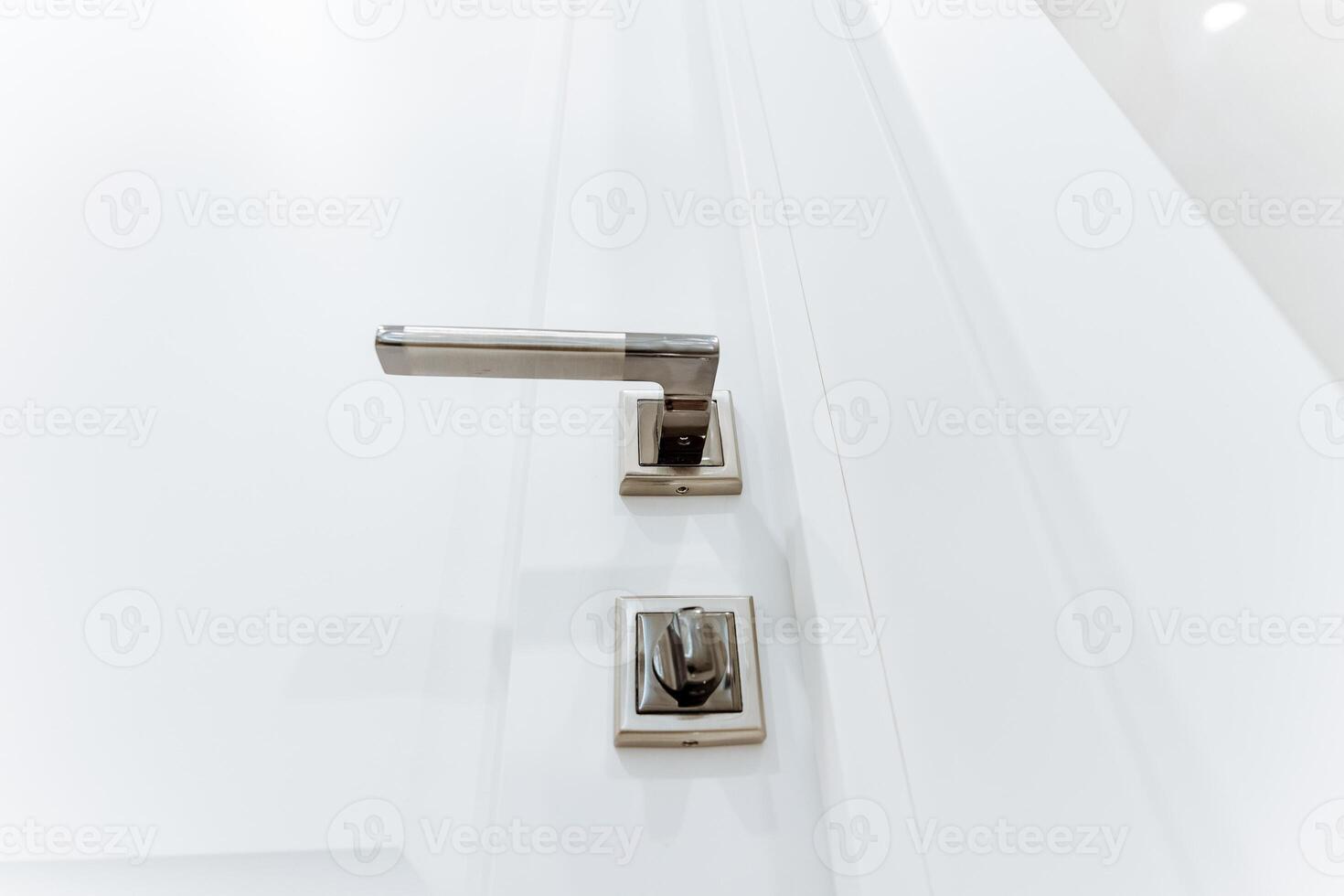 Grey handle on white bathroom door, locking mechanism, bottom view of door handle. photo