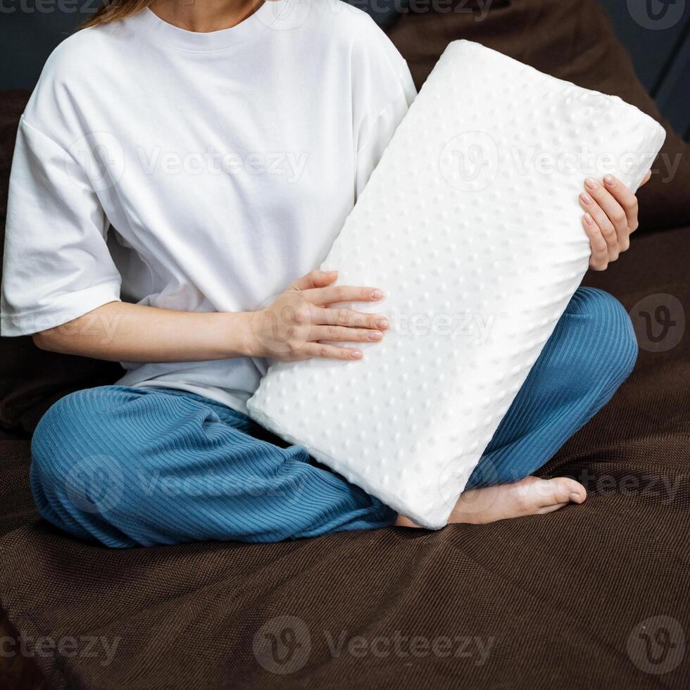 A woman comfortably relaxes on a plush, cozy couch, resting a fluffy white pillow gently on her lap while savoring a welldeserved moment of leisure amidst a calm and serene atmosphere photo