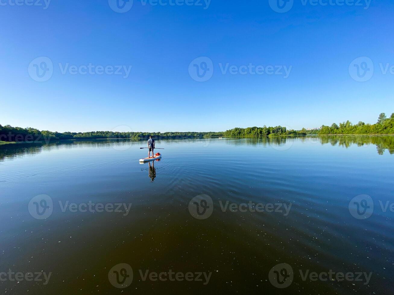A serene scene unfolds as a person peacefully paddles on a tranquil lake, surrounded by natures beauty under a clear sky, creating a calm and peaceful atmosphere in this tranquil setting photo