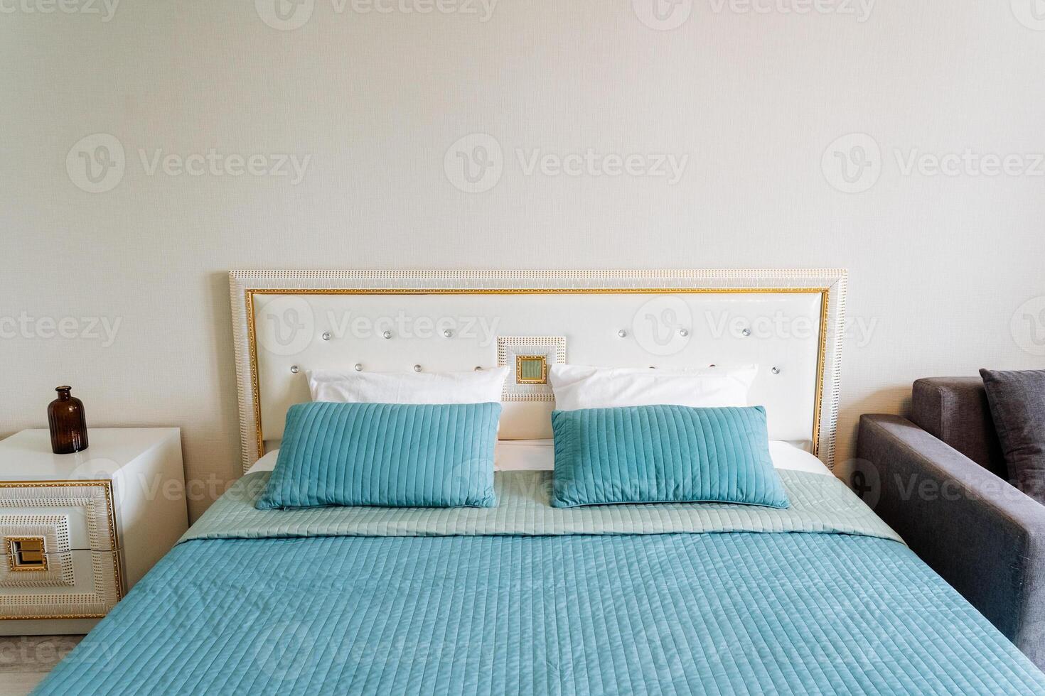 A rectangular wood bed with azure bedding in a bedroom next to a couch photo