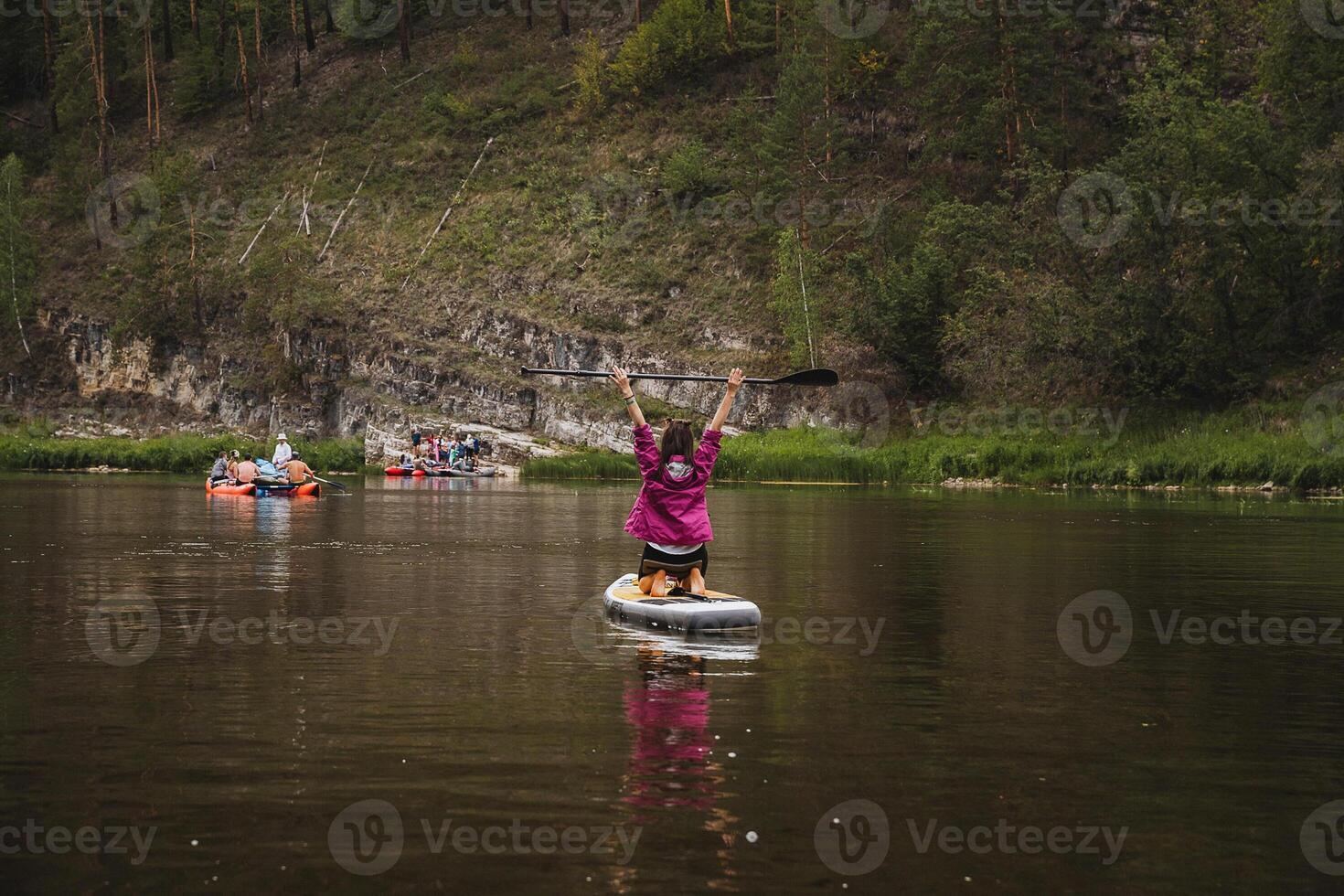 A woman is currently standing on a paddle board while enjoying her time in the water, taking in the surrounding natural scenery and the beauty of the landscape around her photo