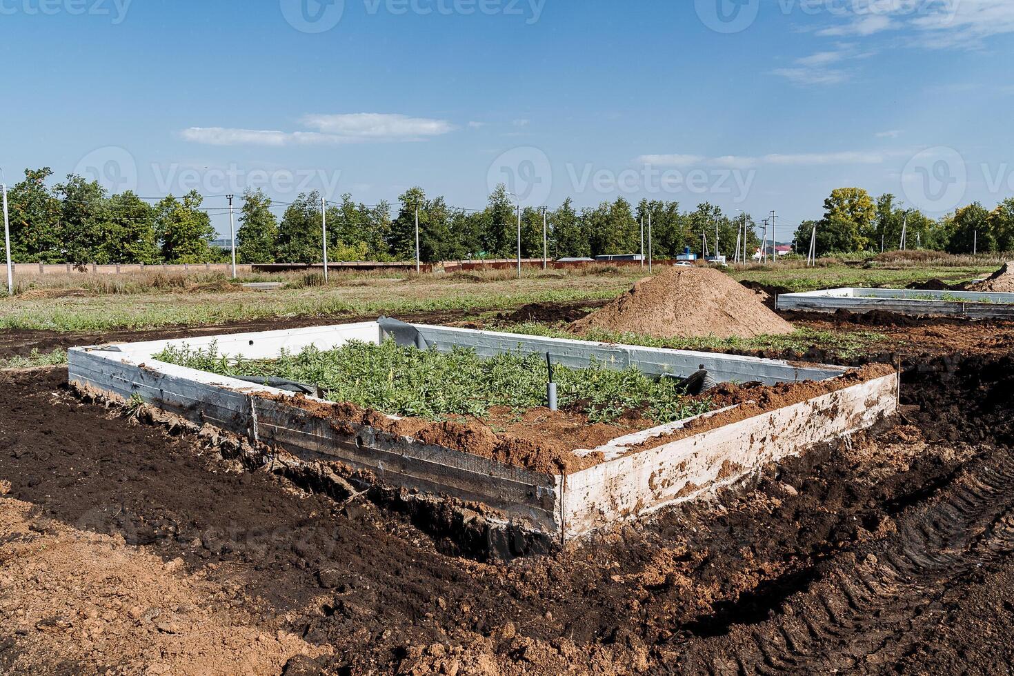 A robust and sturdy concrete foundation for a brand new house is currently being meticulously constructed in a wide, open dirt field that stretches endlessly beneath the expansive sky above photo
