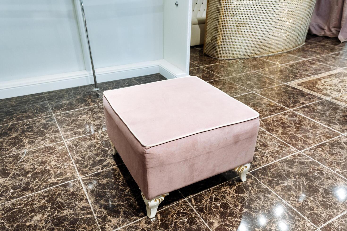 A soft pink ottoman is peacefully placed on a beautifully tiled floor in a charming and cozy room, contributing to an inviting atmosphere filled with comfort, elegance, and style photo