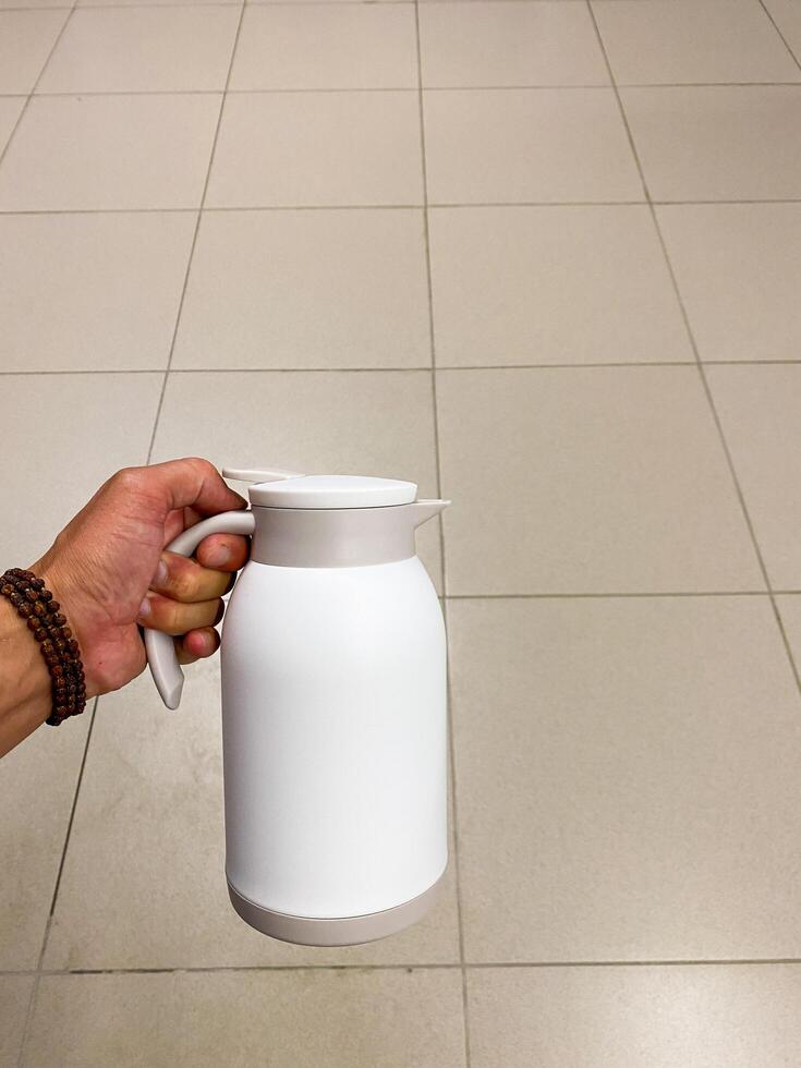 Image shows a person in kitchen with white pitcher, focusing on Gesture, Gas, Kitchen appliance and Milk, with keywords Drinkware, Flooring, Plant milk, Hemp milk, Cylinder photo