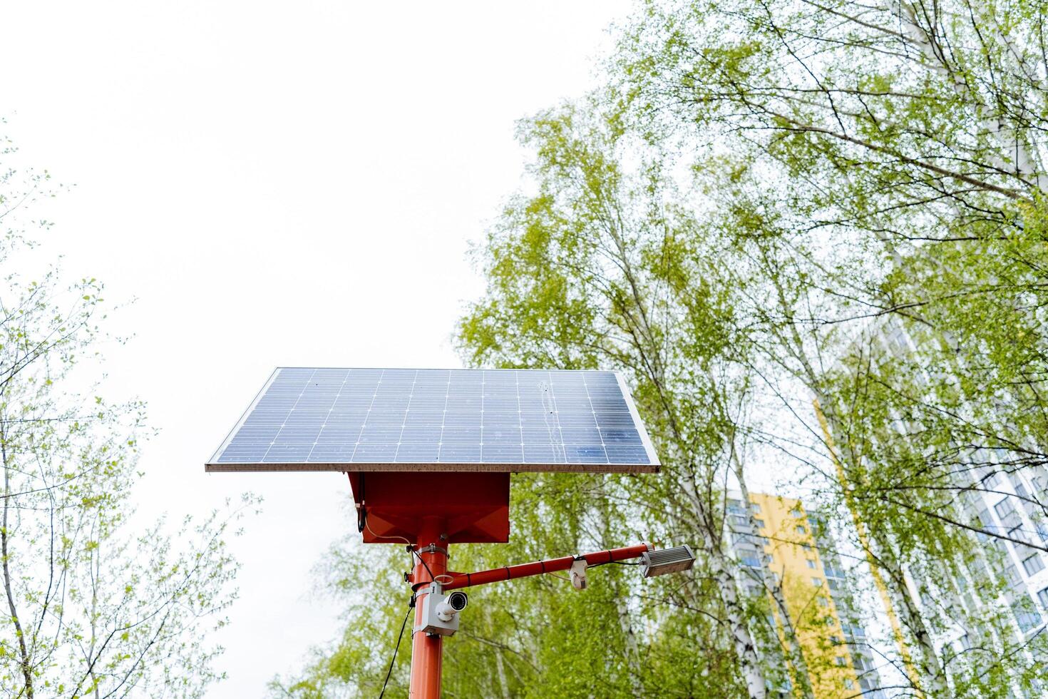 A solar panel rests on a crimson pole under the vast sky photo