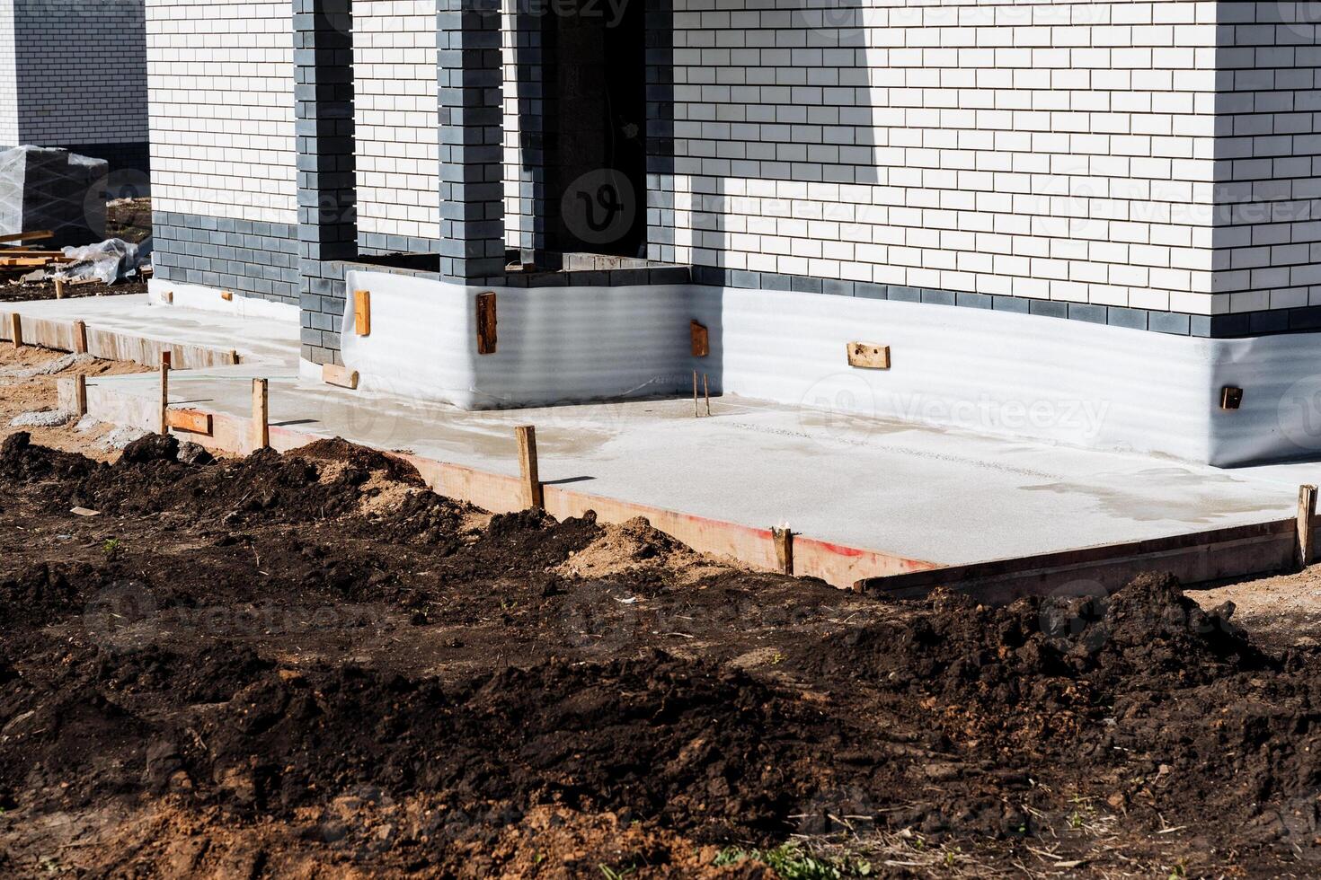 A modern house construction site with brick walls and fresh concrete foundation. The exterior of the unfinished house showcases the use of modern architecture and construction materials photo