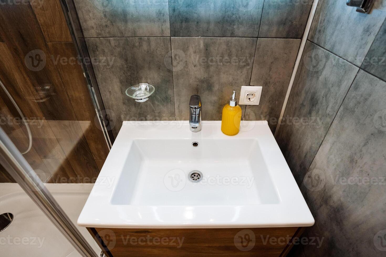 A bathroom sink is situated prominently, featuring a soap dispenser conveniently placed on the counter above it, which enhances both the functionality and aesthetics of the cozy space photo