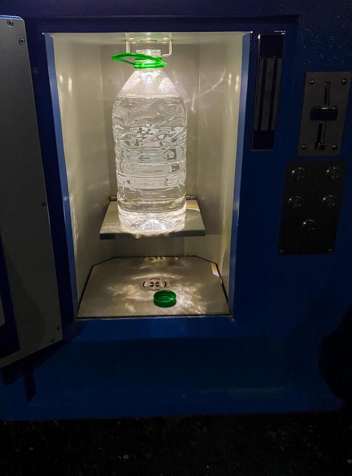 A bottle that is completely filled with refreshing water is currently resting on the inside of a vending machine, eagerly waiting to be purchased by a thirsty customer in need of a drink photo