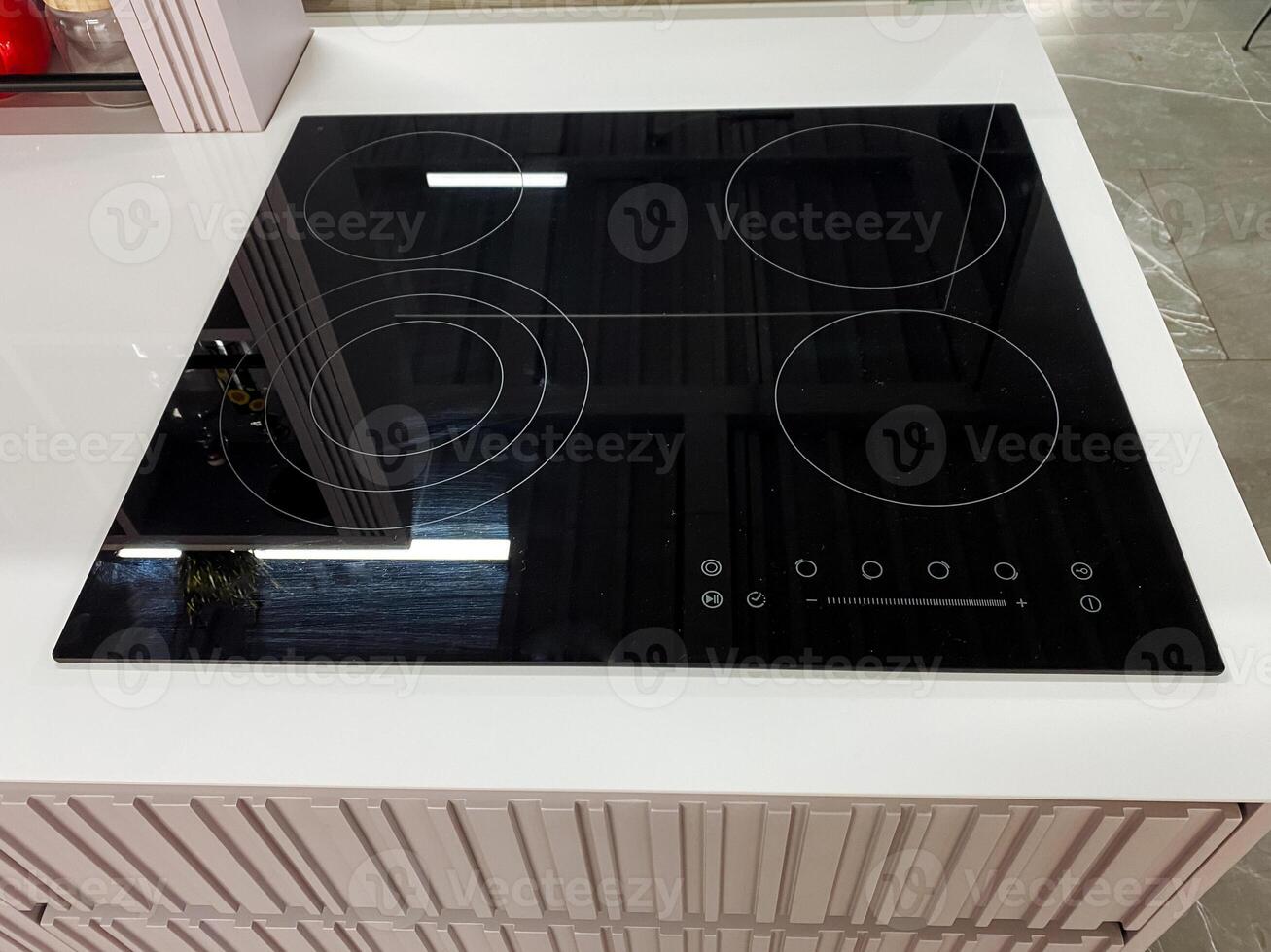 A sleek black stove top oven is elegantly positioned on a pristine white countertop, adding a modern touch to the overall kitchen design and functionality in this home environment photo