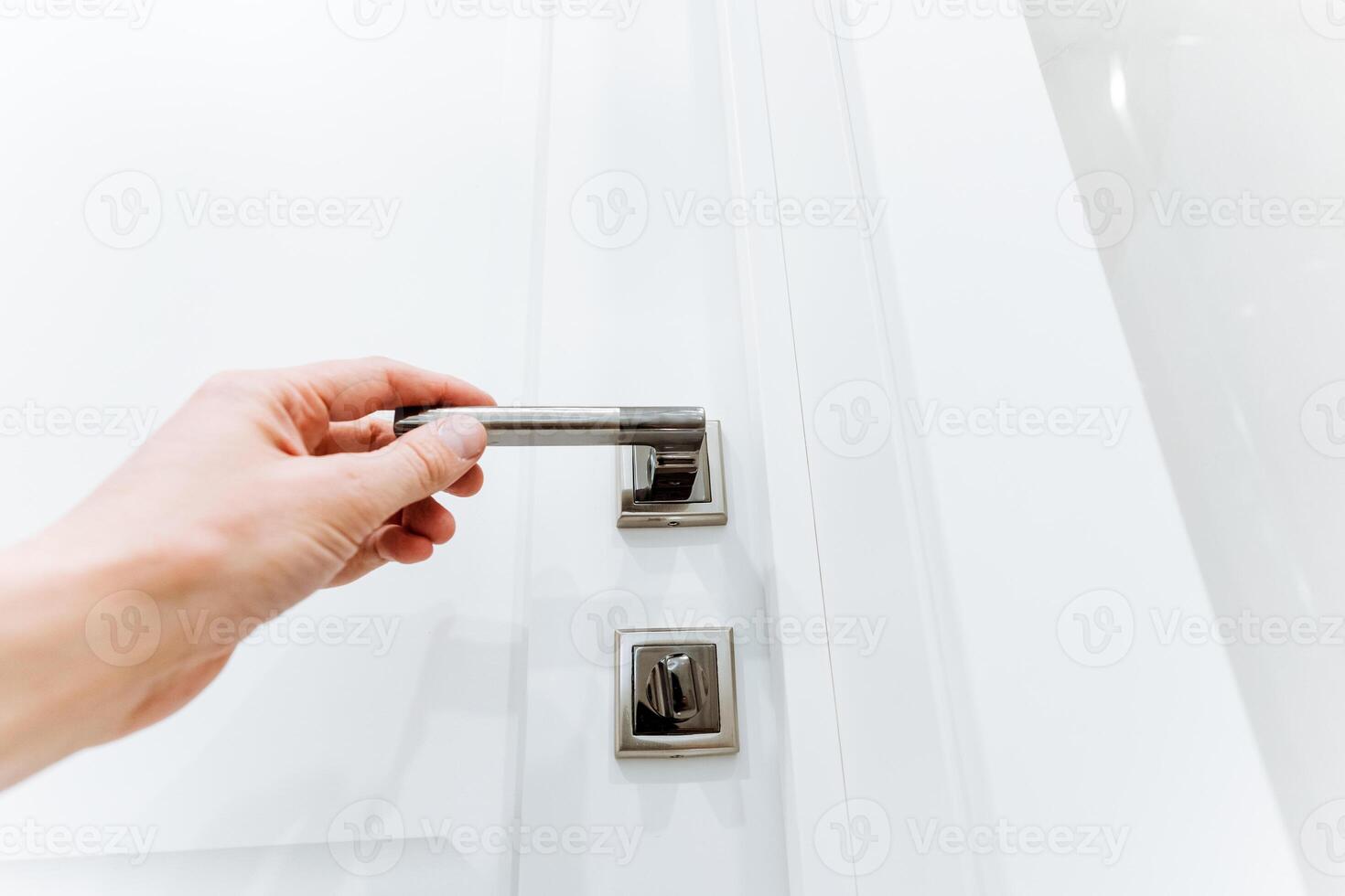 Using a key, the person gestures to open a white door photo