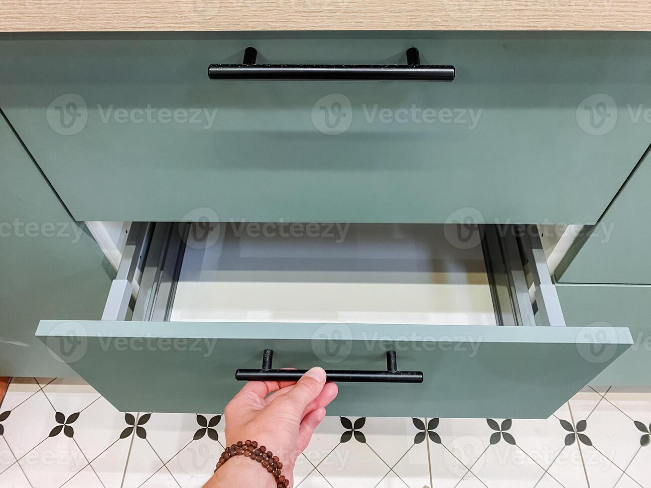 In a wellequipped kitchen, a person meticulously opens a drawer, revealing a diverse array of utensils and essential items crucial for both cooking and food preparation tasks photo