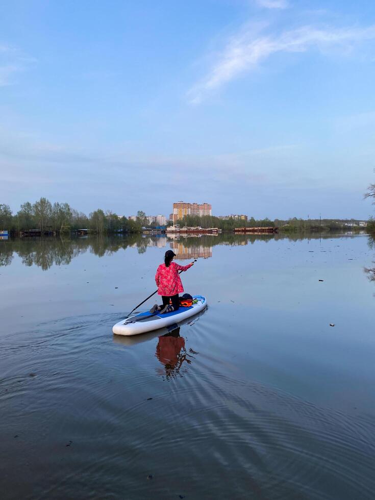 A person is paddleboarding on a calm lake under a clear sky, enjoying the peaceful atmosphere in nature photo