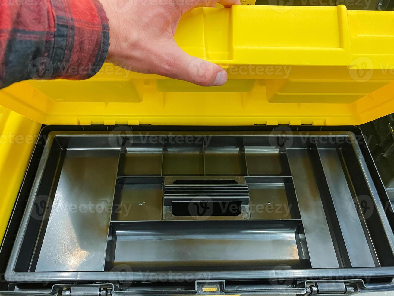 A person is currently in the process of opening a vibrant and bright yellow plastic toolbox that likely holds various tools intended for repair, maintenance, or construction tasks photo