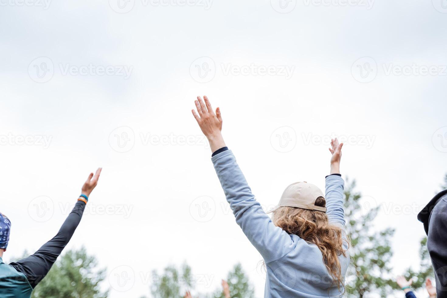 At a lively outdoor event, a diverse group of individuals joyfully come together, raising their arms in unity and celebrating in nature with enthusiasm and happiness photo