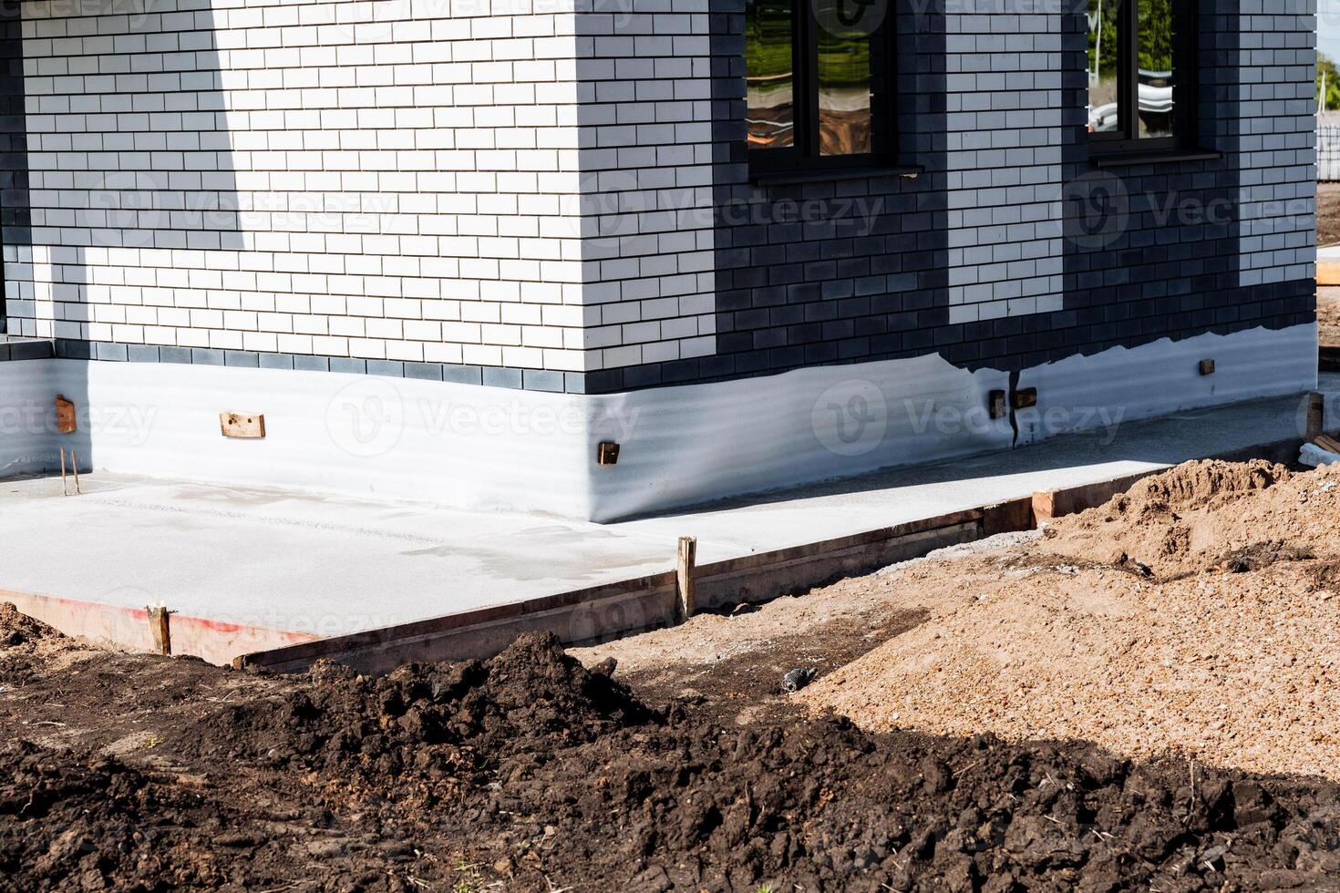 Detailed closeup of the foundation and wall of a newly constructed modern brick house with black and white tiles, showcasing the solid base and modern design of the building photo