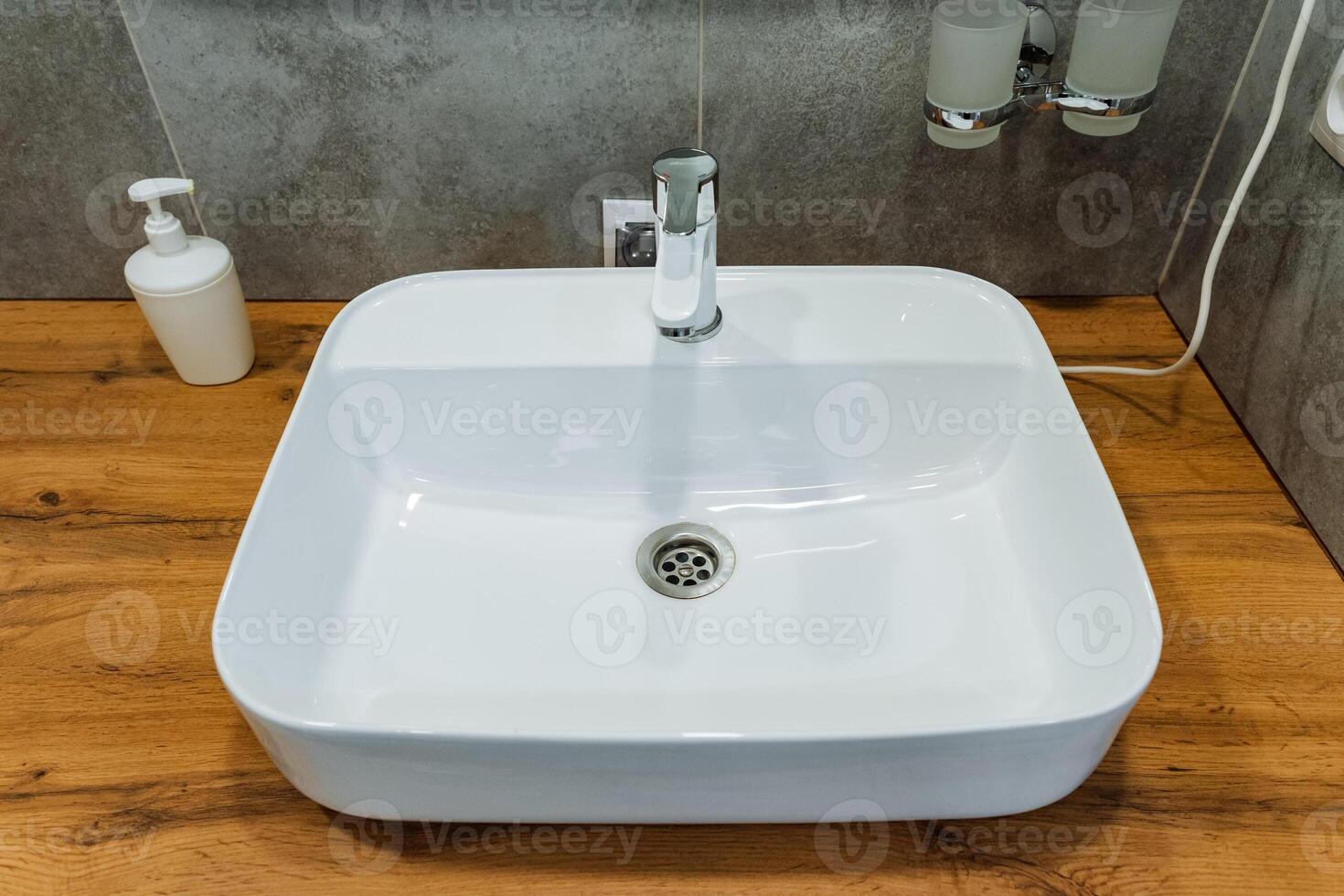 White bathroom sink on wooden counter with plumbing fixtures photo