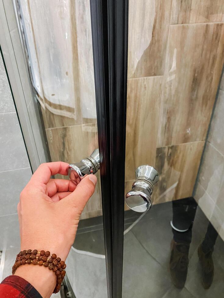 A person is expertly and slowly opening a shower door in a bathroom, preparing for a refreshing shower experience after a long day spent working or engaging in various activities photo