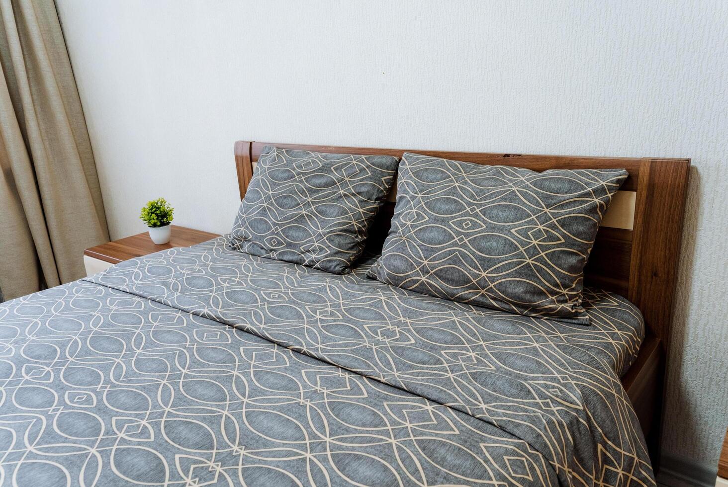 A grey bed frame with hardwood pillows and comforter in a bedroom photo