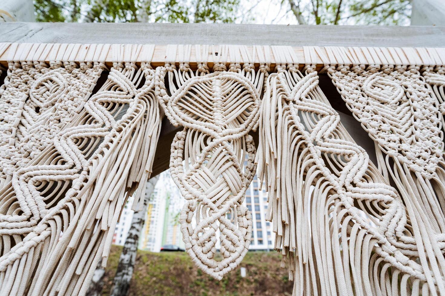 Close up of a textile art macrame wall against a white building facade photo