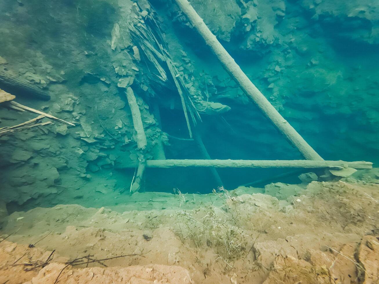 A ladder submerged in water near rocks offers a special underwater perspective, combining leisure, art, and nature in the landscape, highlighting the peacefulness of the setting photo