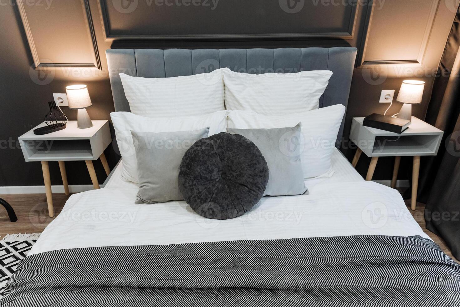 In a cozy bedroom, there is a beautifully made bed adorned with crisp white sheets and fluffy pillows, accompanied by two elegant nightstands on either side for added functionality photo