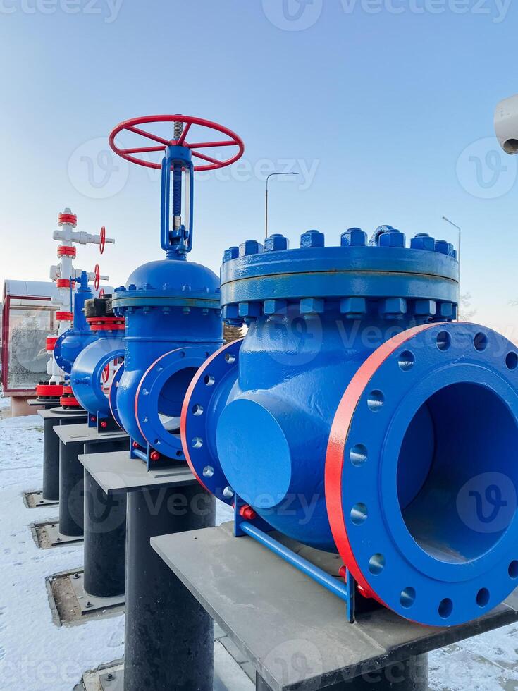 A vivid and colorful row of blue and red valves is lined up neatly in the pristine white snow, creating a striking visual contrast against the stark cold winter landscape all around them photo